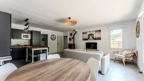 Un salon moderne comprenant une table à manger, un canapé et un coin cuisine équipé d’un four à micro-ondes et de placards.
