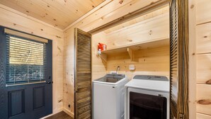 A compact laundry room with two washing machines, a drying rack, and a small shelf with a bottle. - Peaceful Mountain Escape with Ridge Views & Hot Tub (Maggie Valley)