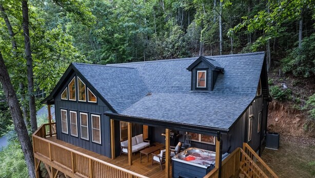 Eine Hütte mit einer Terrasse, einem Whirlpool und einer überdachten Sitzgruppe im Freien.