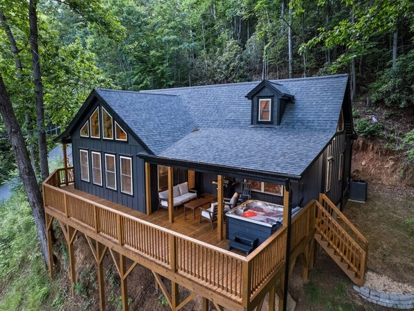 Eine Hütte mit einer Terrasse, einem Whirlpool und einer überdachten Sitzgruppe im Freien.