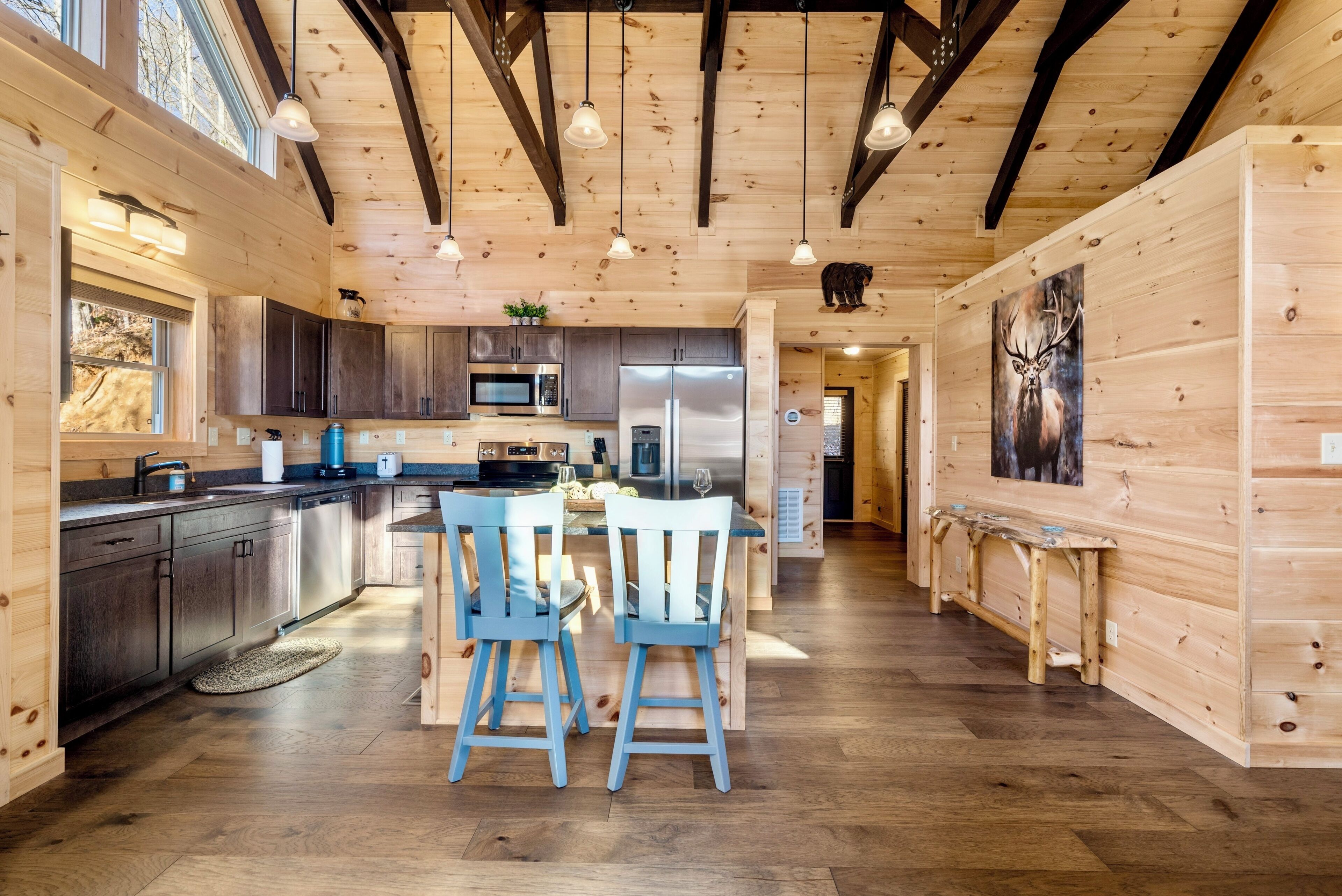 Cocina moderna con armarios de madera, electrodomésticos de acero inoxidable y un comedor con dos sillas azules.
