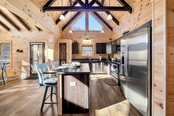 A wooden interior with a kitchen island, dining area, and a large refrigerator.
