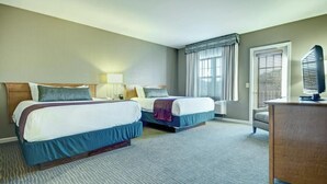 A hotel room with two beds, a desk, a chair, and a large window with blinds. - Unleash Your Alpine Adventure: Wyndham Bentley Brook Ski-In, Ski-Out Resort  (Hancock)