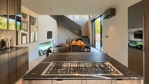A modern kitchen with a central island, dark countertops, and a stainless steel stove.