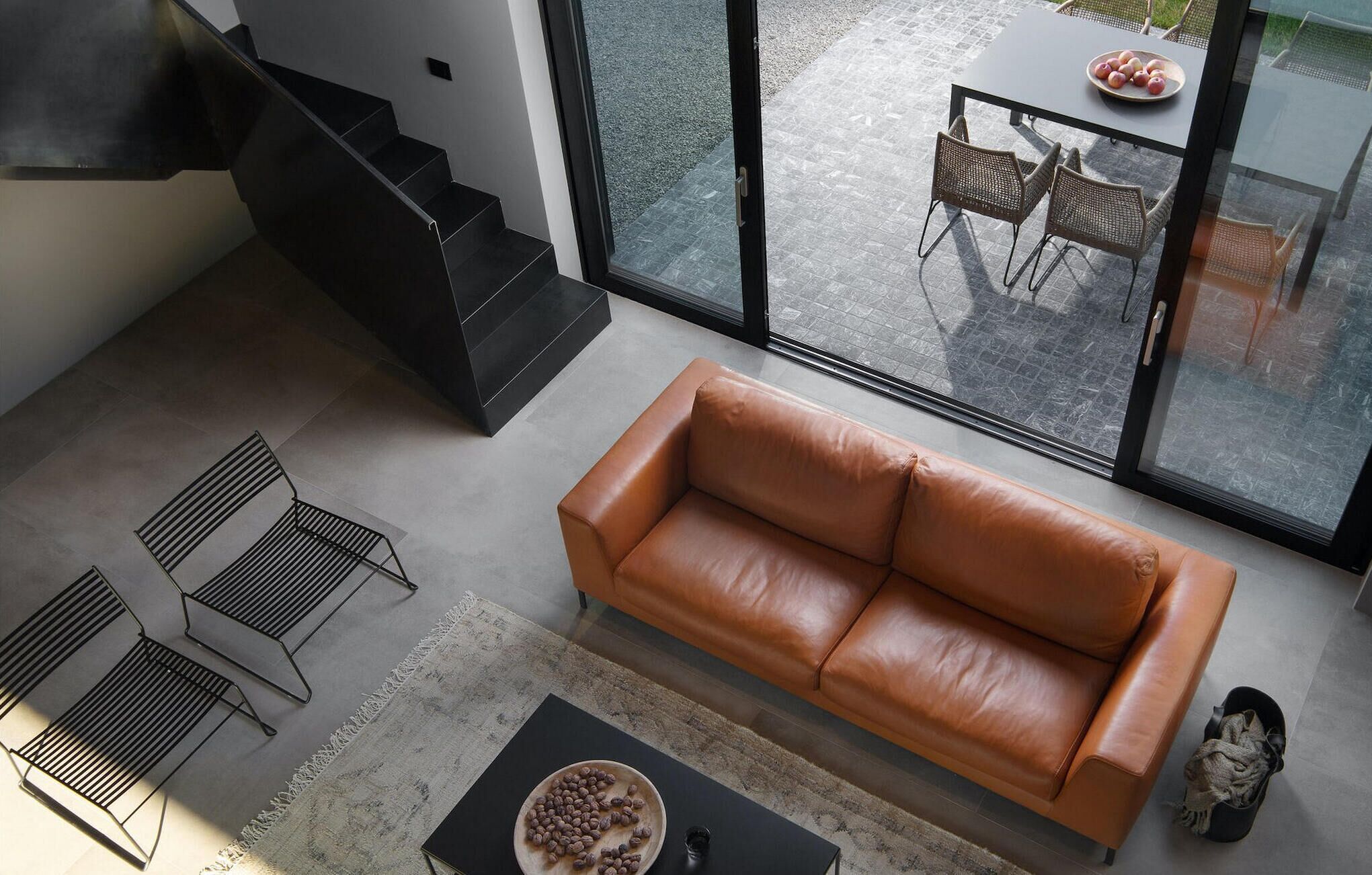 A modern living room with a leather sofa, a coffee table, and a staircase.