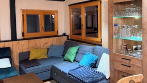 Una sala de estar acogedora con un sofá seccional, armarios de madera y una vitrina de vidrio.