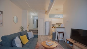 A modern apartment with a living room, kitchen, and dining area. - 5BR CozySuites The Block-SkybridgeAccess (Indianapolis)