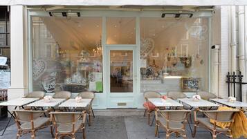 A cafe with wicker chairs and tables, a glass door entrance, and a view of the street.