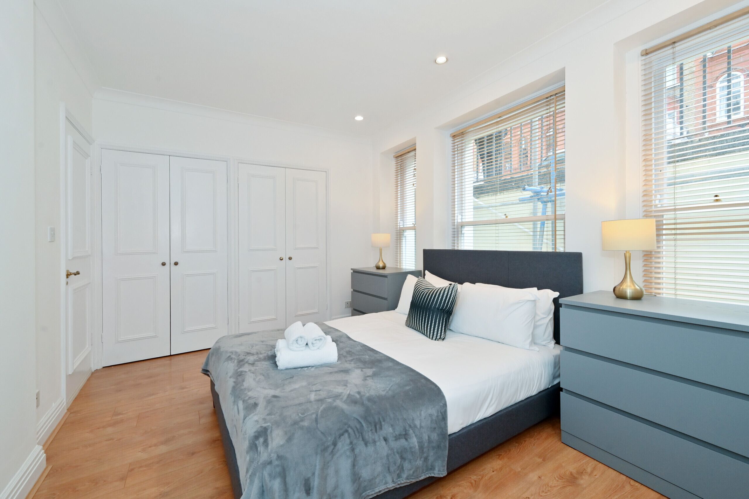A bedroom with a bed, bedside tables, a wardrobe, and a window with blinds.