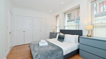 A bedroom with a bed, bedside tables, a wardrobe, and a window with blinds.