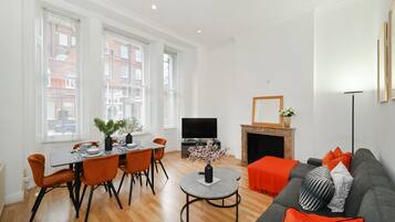 A modern living room with a dining area, a fireplace, and a television.