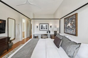 A hotel room with a large bed, a desk with a chair, a television, and artwork on the walls. - New Luxury Home | Heated Pool & Spa (New Orleans)