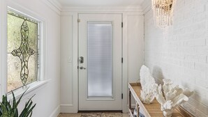 A white door with a window, a decorative wall, and a chandelier.