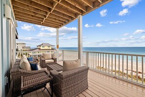 A covered outdoor seating area with wicker furniture and a view of the beach.