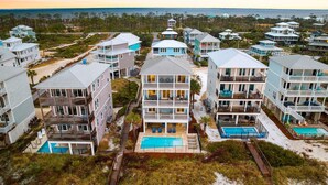 A coastal residential area with multiple two-story houses featuring balconies, a central swimming pool, and a beach in the background. - Family Beach Retreat w/Pool and Elevator (Port St. Joe)