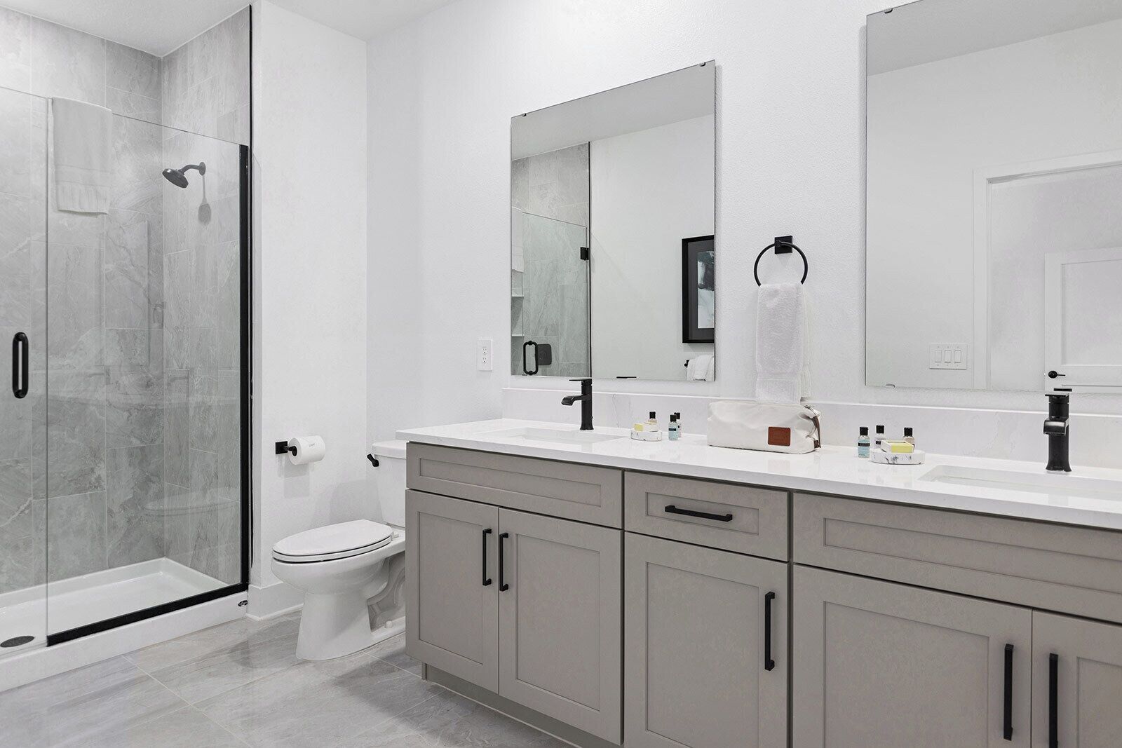 Un baño moderno con cabina de ducha de vidrio, inodoro, tocador con espejo y lavamanos.
