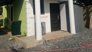A small, single-story building with a green and white facade, a front door, and a small porch area. - Cutest House in Tema and Afienya (Tema)