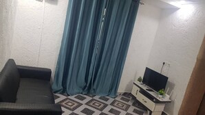 A living room with a sofa, a TV on a stand, and a patterned floor. - Cutest House in Tema and Afienya (Tema)