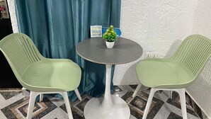 A small round table with a white base, two green chairs, a potted plant, and a blue curtain in the background. - Cutest House in Tema and Afienya (Tema)