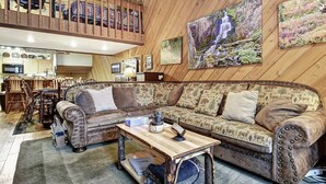 A cozy living room with a large sofa, a wooden coffee table, and a dining area with chairs and a table.