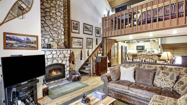 A cozy living room with a stone fireplace, a flat-screen TV, and a comfortable sofa.
