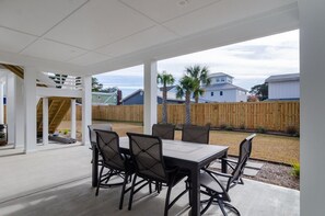 An outdoor patio with a table and chairs, a wooden fence, and a view of neighboring houses.