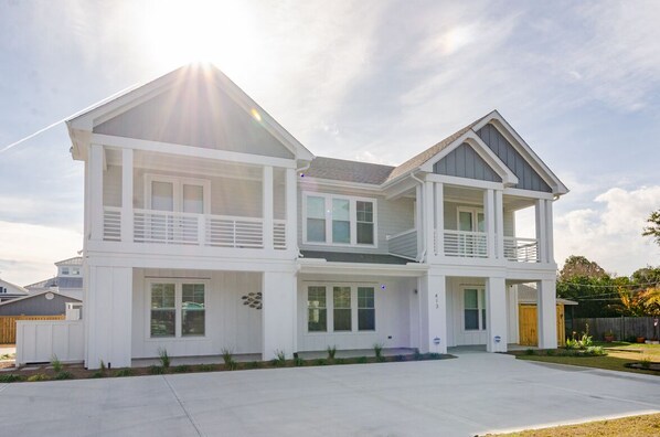 A two-story house with a balcony on the upper floor, a front porch, and a driveway.