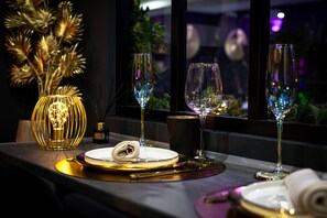 A table set with a candle, wine glasses, and a decorative vase. - Love Room « La Nuit de Rêve » (Perpignan)