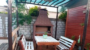 Un patio al aire libre con un horno de ladrillo, bancos de madera y una mesa.