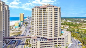 Ein Hochhaus-Hotel mit mehreren Balkonen, einer Tiefgarage und Blick auf Strand und Meer.
