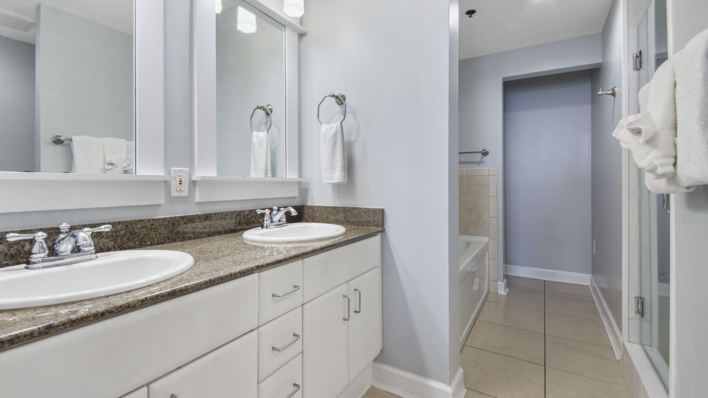 A modern bathroom with two sinks, a large mirror, and a shower area.