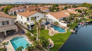 A residential area with a large swimming pool, multiple houses, and a marina.