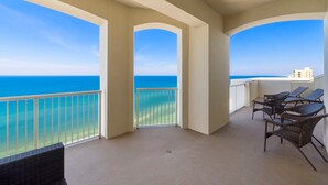 Un balcon avec vue sur l’océan, comprenant une balustrade, une chaise et une petite table.