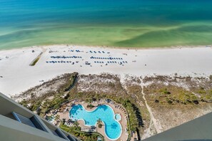 Vista aérea de un resort con una gran piscina, zona de playa y aguas azul turquesa.