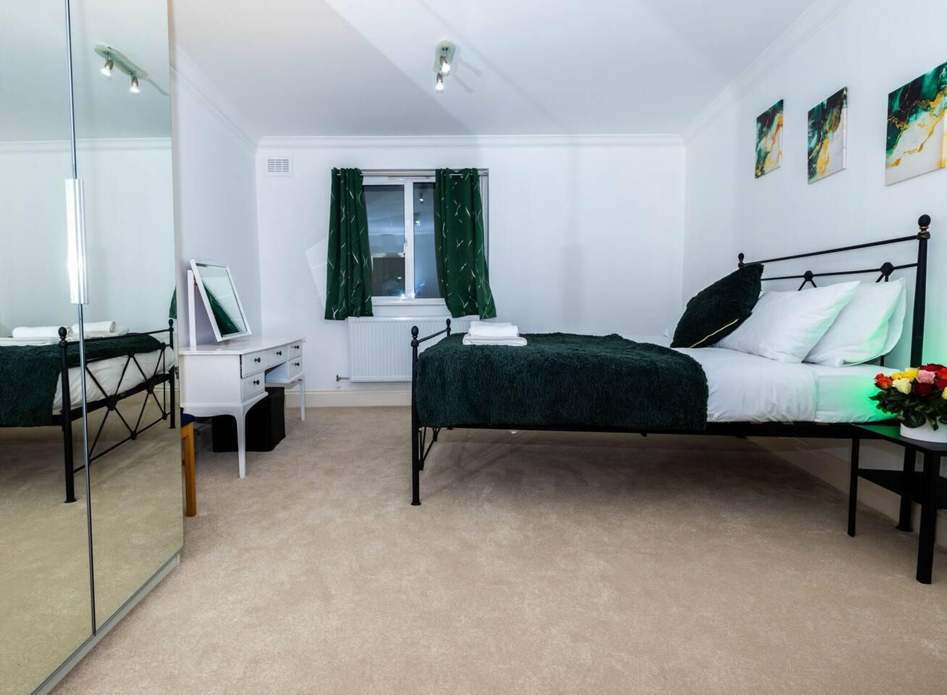 A bedroom with a bed, a desk, a mirror, and a radiator.