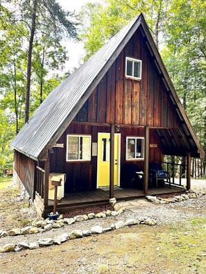 Une cabane en bois avec une véranda, une porte et une fenêtre.