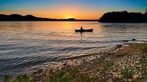 Une rivière paisible au coucher du soleil, avec un bateau au centre.