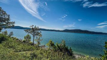 A lake with clear water, surrounded by trees and hills.