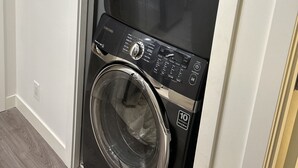 Una lavadora y secadora apiladas con un panel de control, una etiqueta de garantía de 10 años y un botón de encendido.