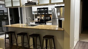Una cocina moderna con una isla central, taburetes de bar, electrodomésticos de acero inoxidable y un letrero que dice 'Bebiendo buena cerveza con buenos amigos'.