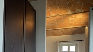 A spacious room with a large wardrobe, a chair, and a view through a window with curtains. - Luxury home with pool and spectecular views (Piemonte)