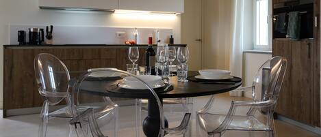 Une cuisine moderne avec une table à manger ronde, des chaises transparentes et un four encastré.