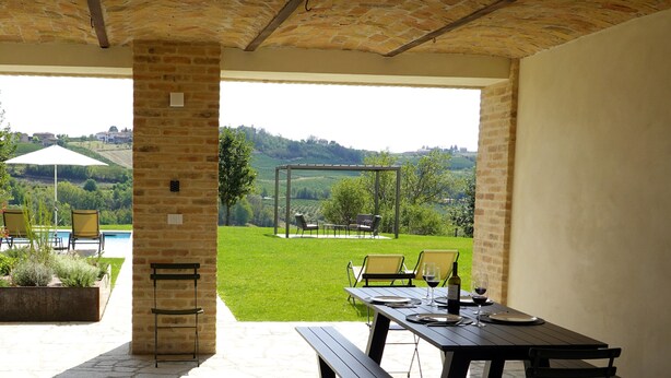 An outdoor patio with a stone floor, a picnic table, and chairs. - Luxury home with pool and spectecular views (Piemonte)