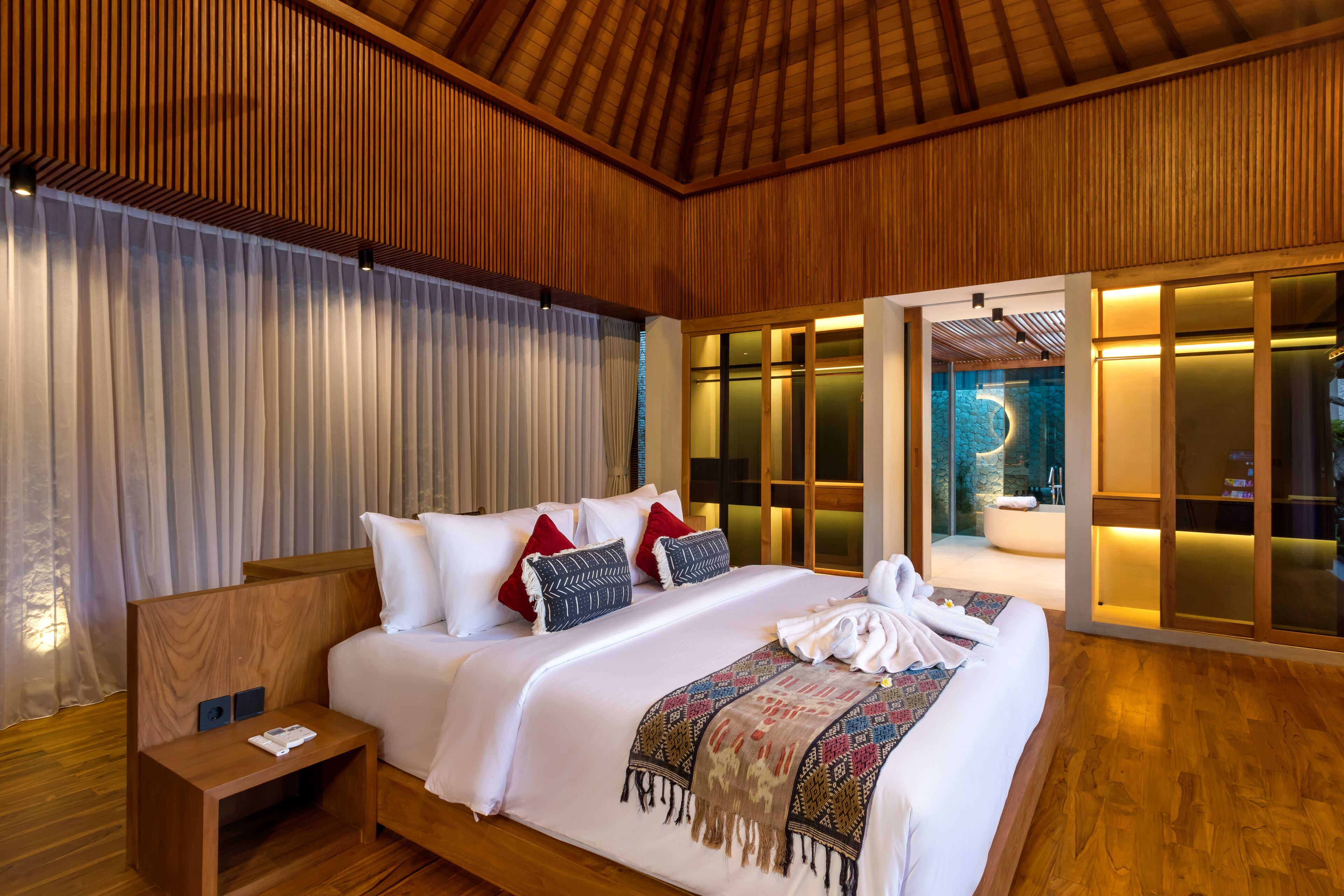Un dormitorio espacioso con una cama grande, cabecero de madera y vistas a un área de spa.