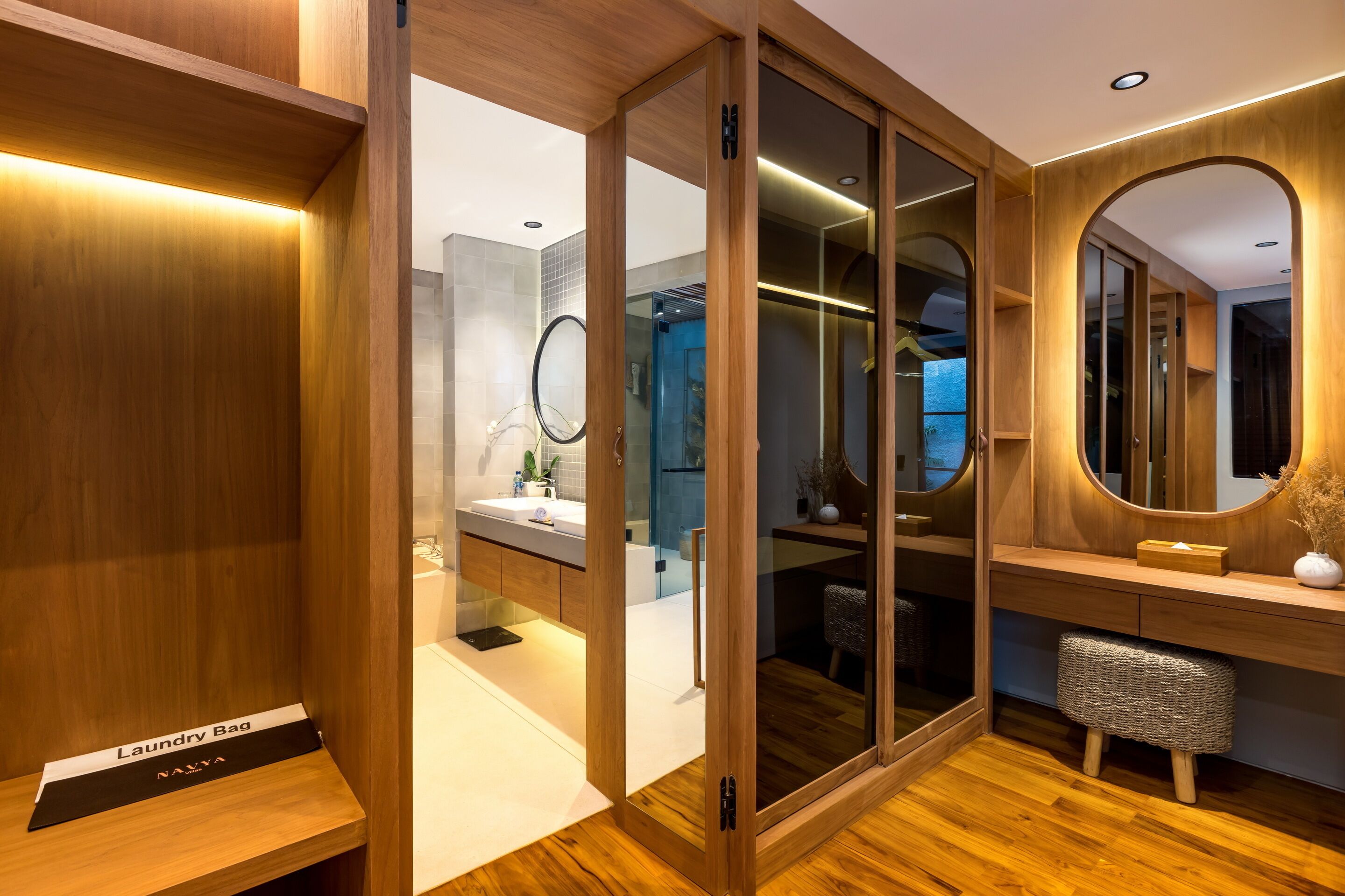 Une salle de bain moderne avec un meuble-lavabo en bois, une cabine de douche en verre et un miroir rond.