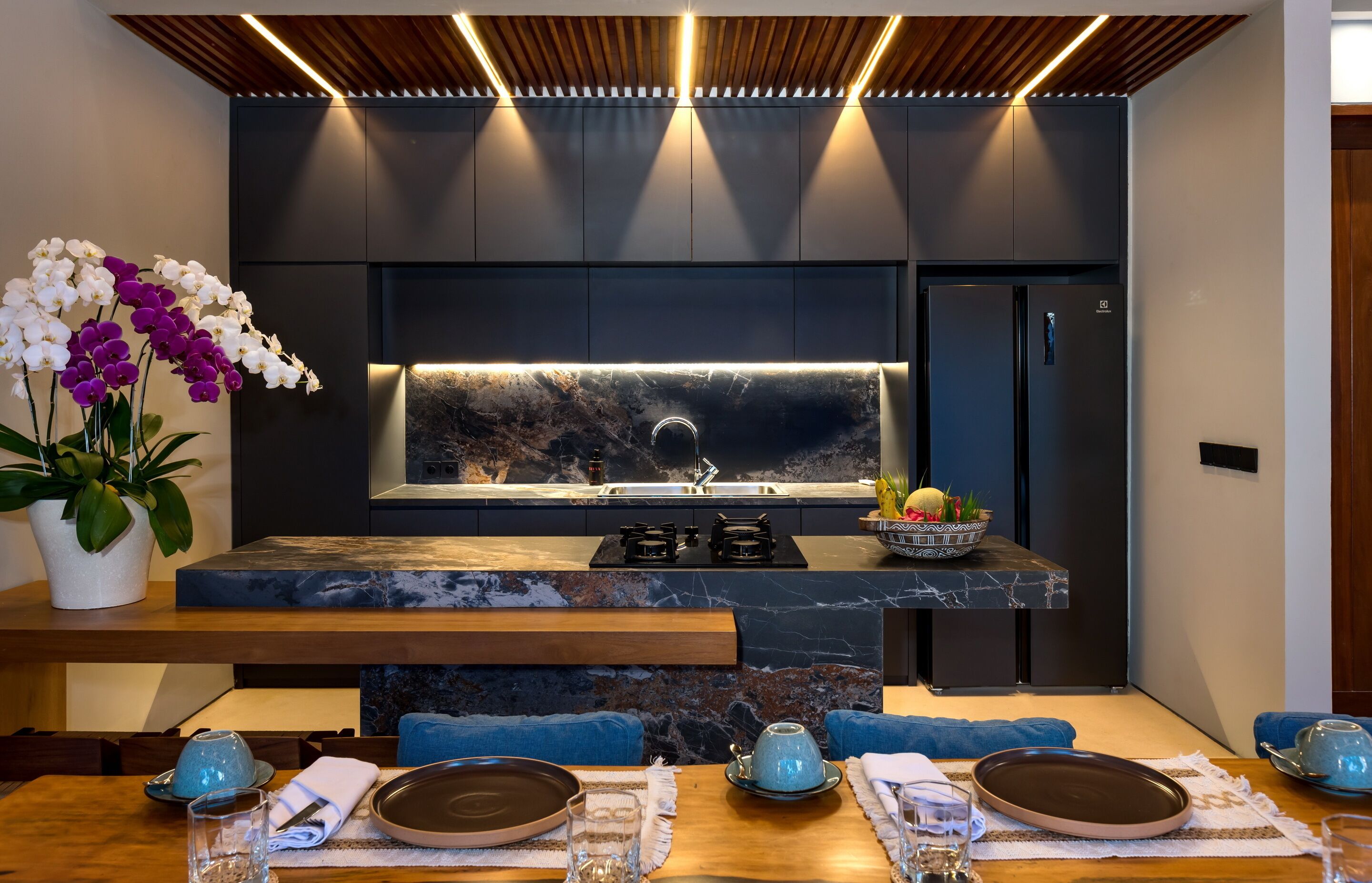 Una cocina moderna con encimera de mármol, electrodomésticos integrados y una isla central con asientos.