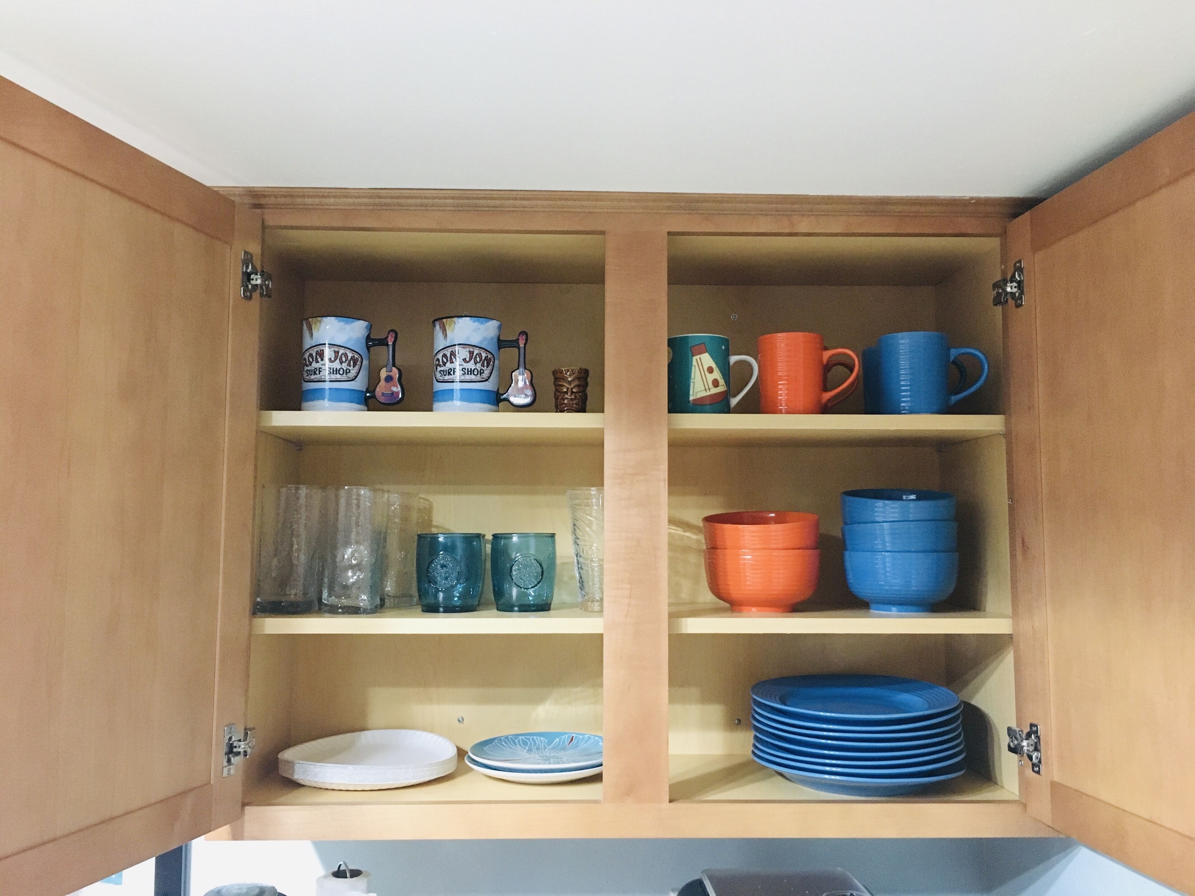 Un aparador de madera con estantes que contienen varias tazas, platos y cuencos.