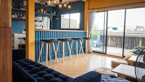 A modern interior with a bar area, seating, and large windows. - Ti Thong Hostel (Bangkok)
