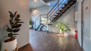 A modern interior with a staircase, potted plants, and a fire extinguisher. - Ti Thong Hostel (Bangkok)