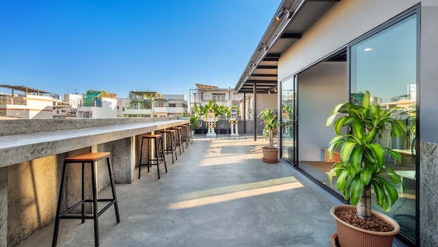 A rooftop bar with concrete flooring, bar stools, and potted plants. - Ti Thong Hostel (Bangkok)